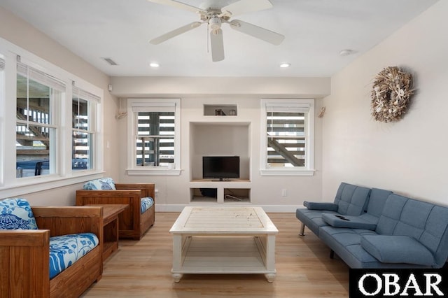 living area with visible vents, baseboards, a ceiling fan, and light wood finished floors