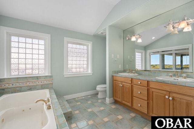 bathroom featuring double vanity, a tub with jets, lofted ceiling, and a sink