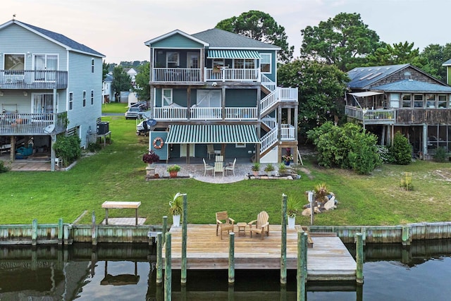 rear view of house featuring a patio, a lawn, and a water view