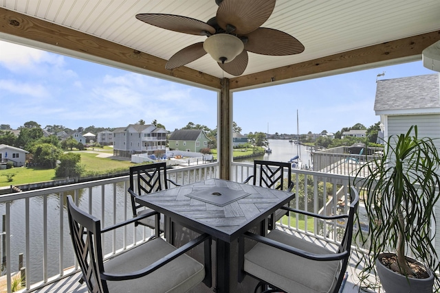 balcony with a water view, a residential view, a ceiling fan, and outdoor dining space