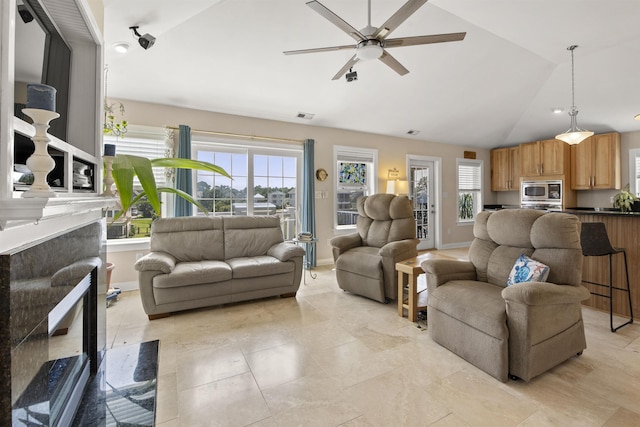 living area featuring plenty of natural light, visible vents, vaulted ceiling, and a ceiling fan