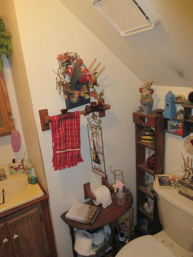 bathroom with toilet, lofted ceiling, and vanity