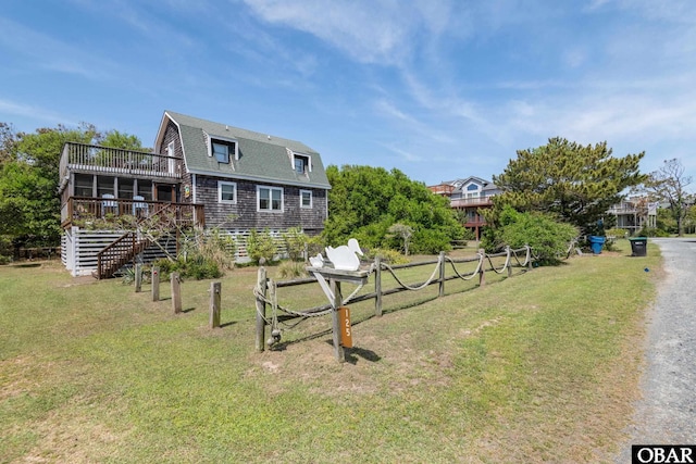 exterior space featuring a deck, a yard, fence, a gambrel roof, and roof with shingles