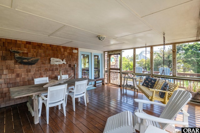 sunroom with hardwood / wood-style floors, expansive windows, and a wooden deck