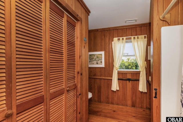 bathroom featuring visible vents, toilet, and wooden walls