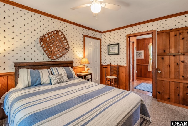 bedroom featuring ornamental molding, wainscoting, wood walls, and carpet