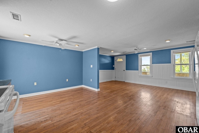 unfurnished living room featuring a ceiling fan, a textured ceiling, and a wainscoted wall