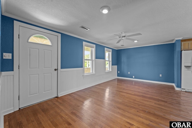 entryway featuring wood finished floors, a ceiling fan, visible vents, and a textured ceiling