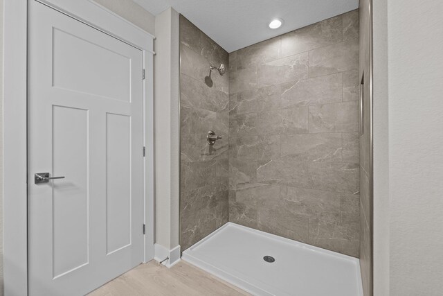 bathroom featuring tiled shower and wood finished floors