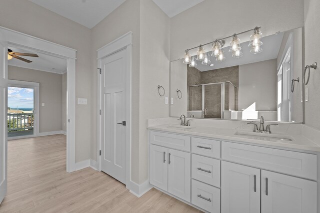 full bathroom with double vanity, a stall shower, wood finished floors, and a sink