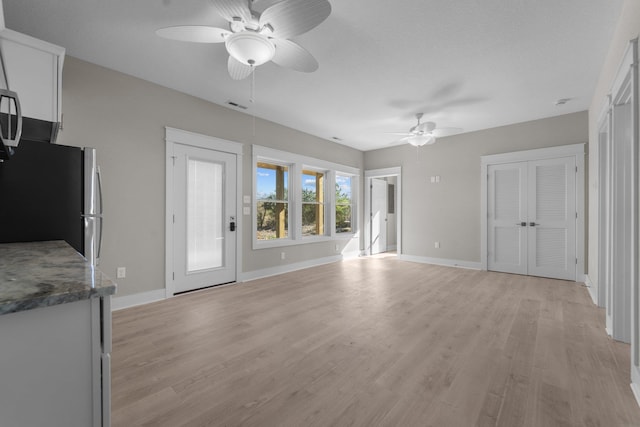 unfurnished living room with light wood finished floors, visible vents, and baseboards