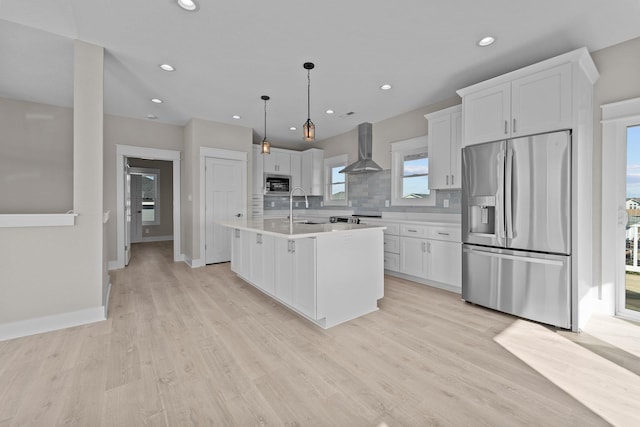 kitchen with light countertops, appliances with stainless steel finishes, white cabinetry, wall chimney exhaust hood, and tasteful backsplash