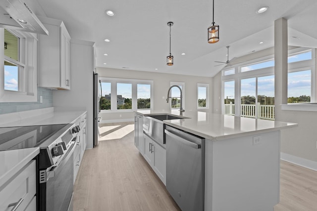 kitchen with backsplash, appliances with stainless steel finishes, a center island with sink, and white cabinetry