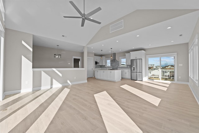 unfurnished living room featuring baseboards, visible vents, high vaulted ceiling, light wood finished floors, and a sink