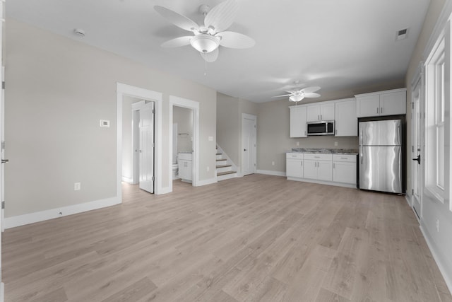 kitchen with visible vents, appliances with stainless steel finishes, white cabinets, light wood finished floors, and baseboards