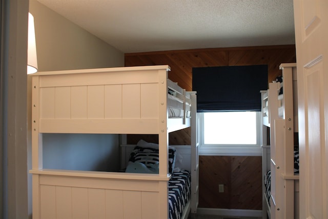 unfurnished bedroom featuring a textured ceiling and wooden walls