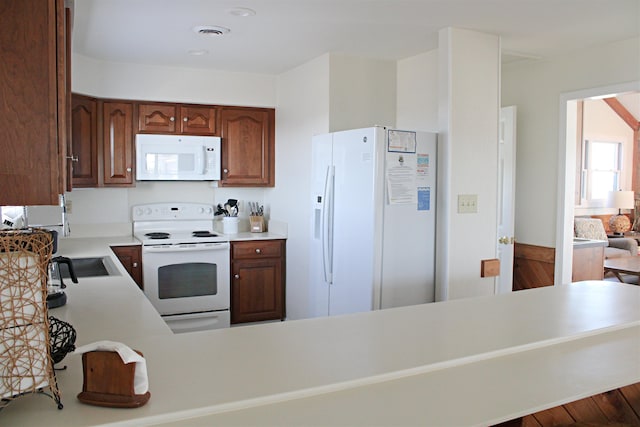 kitchen with light countertops, white appliances, visible vents, and a peninsula