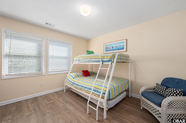 bedroom featuring baseboards, visible vents, and wood finished floors