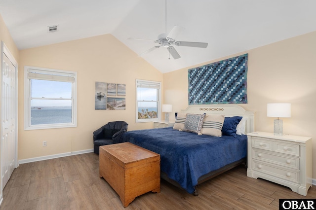 bedroom with vaulted ceiling, wood finished floors, visible vents, and baseboards