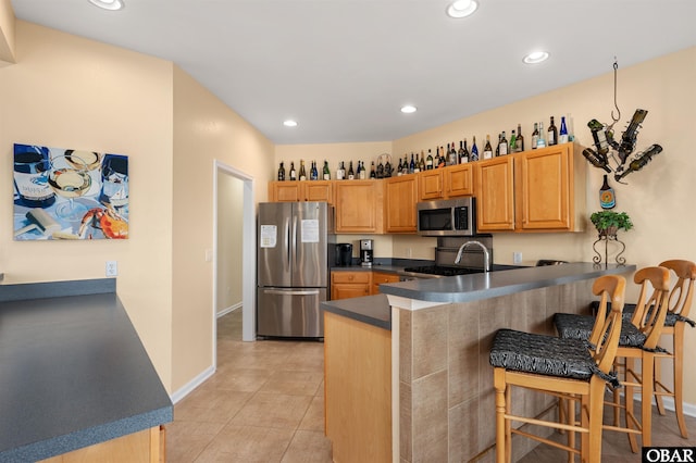 kitchen featuring light tile patterned floors, dark countertops, appliances with stainless steel finishes, a peninsula, and recessed lighting