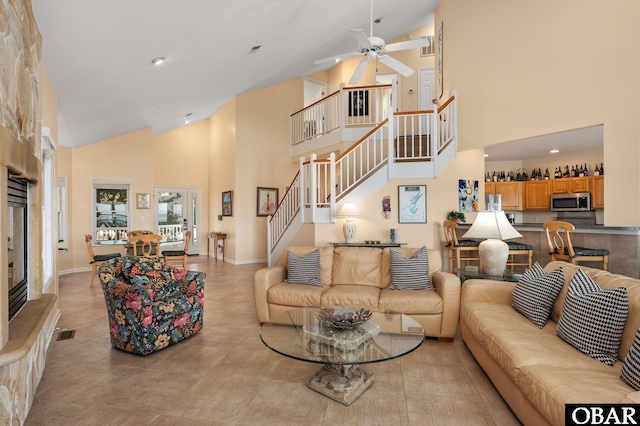 living area featuring high vaulted ceiling, ceiling fan, stairs, and baseboards