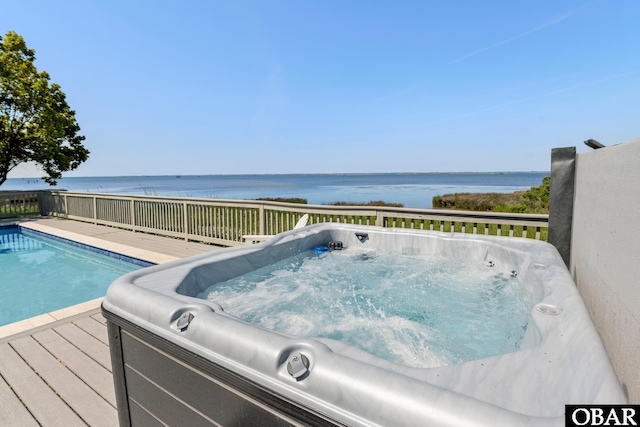 view of pool featuring a deck with water view and a hot tub