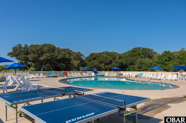 community pool with a patio and fence