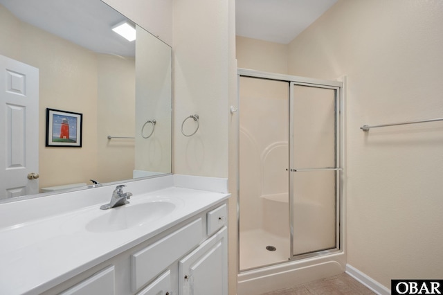 bathroom with a stall shower, baseboards, and vanity