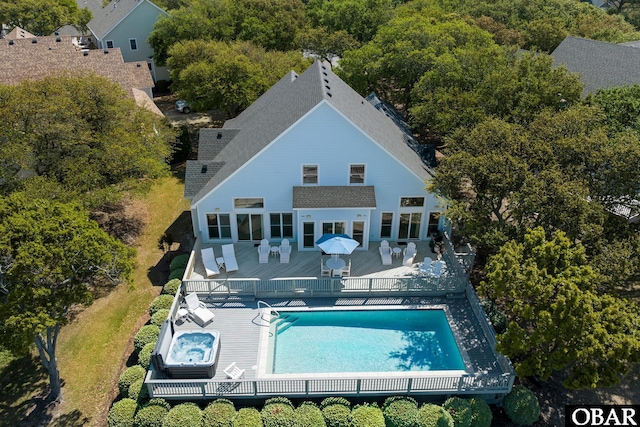 rear view of property featuring a deck, a community hot tub, outdoor dining space, and a community pool