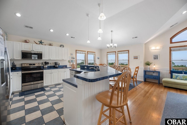 kitchen featuring a sink, visible vents, appliances with stainless steel finishes, wainscoting, and dark countertops