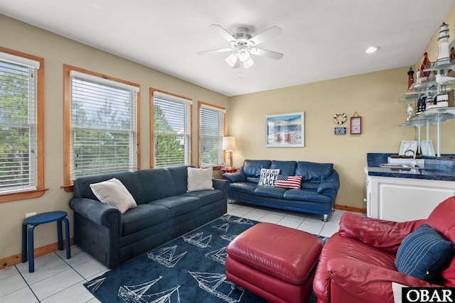 tiled living room featuring ceiling fan, a sink, and baseboards