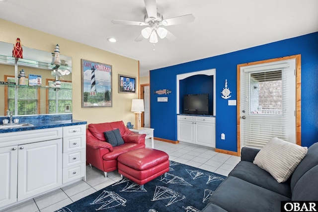 living area with light tile patterned floors, ceiling fan, and baseboards