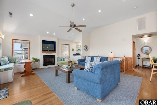 living area with lofted ceiling, a fireplace, visible vents, and light wood-style floors