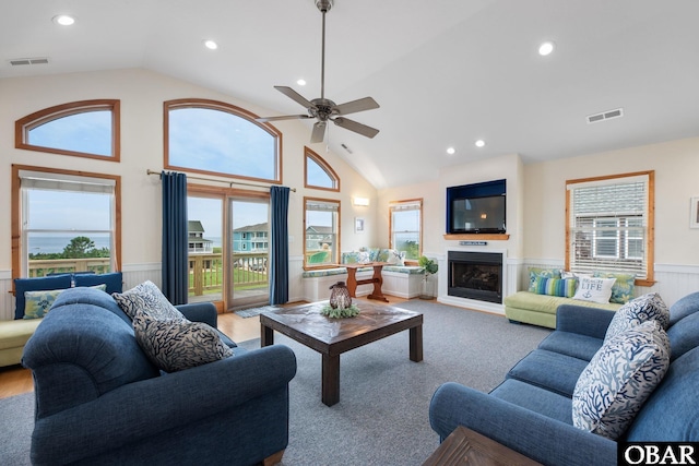 carpeted living room featuring plenty of natural light, a fireplace, visible vents, and wainscoting