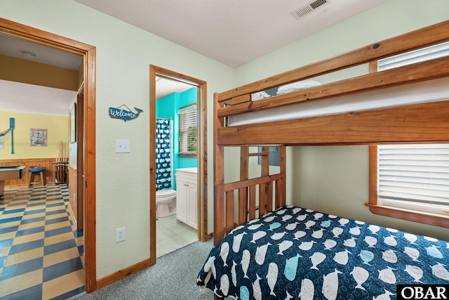 bedroom with carpet floors, visible vents, and ensuite bathroom