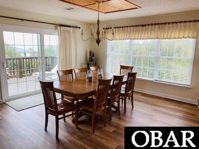 dining space with plenty of natural light, baseboards, a textured ceiling, and wood finished floors