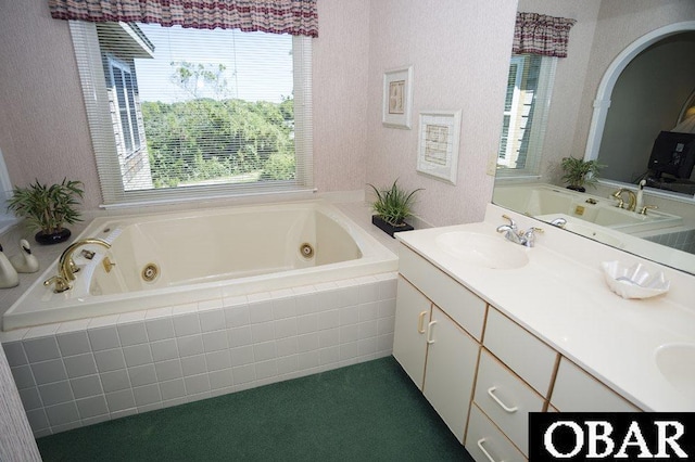 bathroom featuring a textured wall, double vanity, a tub with jets, and a sink