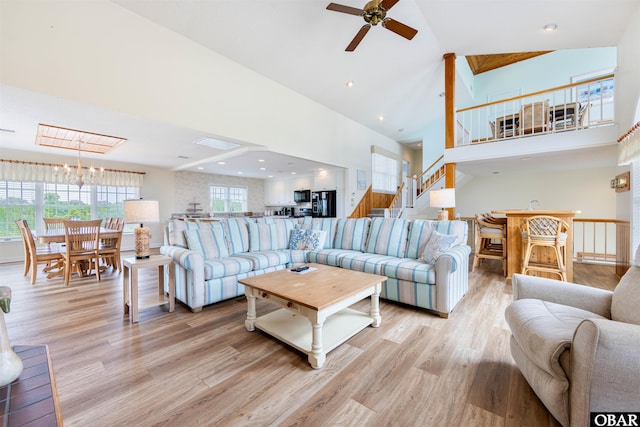 living area featuring light wood finished floors, recessed lighting, a towering ceiling, stairway, and ceiling fan with notable chandelier