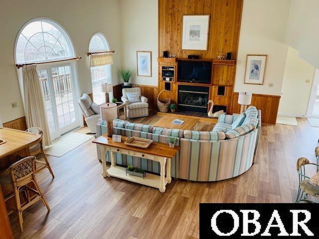 living area with a glass covered fireplace, a high ceiling, and light wood finished floors