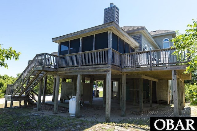 rear view of house featuring a sunroom, a chimney, stairway, and a deck