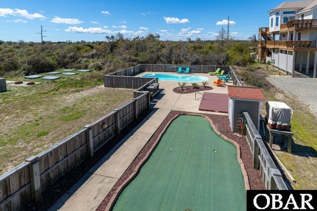 view of home's community featuring an outbuilding, a patio, a fenced backyard, a pool, and a storage unit