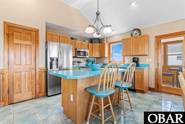 kitchen featuring stainless steel appliances, a kitchen island, a kitchen breakfast bar, light countertops, and decorative light fixtures