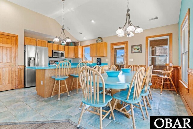 dining area with lofted ceiling, a wainscoted wall, visible vents, and an inviting chandelier