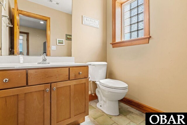 half bathroom with visible vents, baseboards, vanity, and toilet