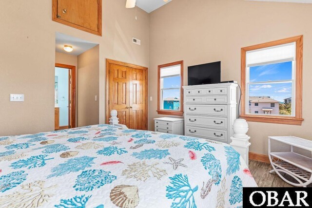 bedroom with a closet, visible vents, baseboards, and wood finished floors