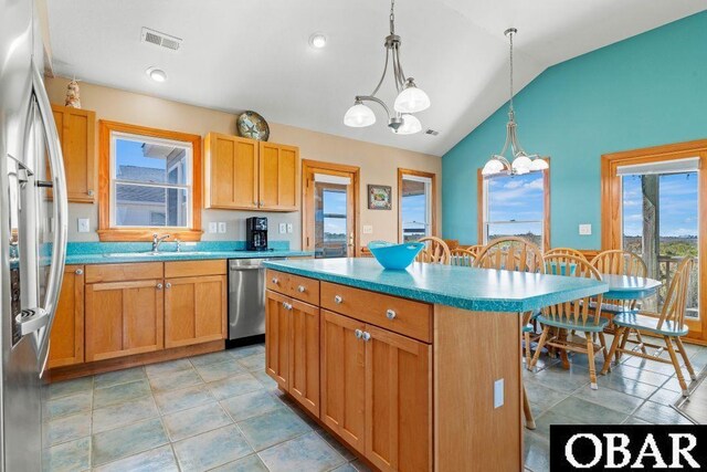 kitchen featuring decorative light fixtures, stainless steel appliances, visible vents, a kitchen island, and a kitchen breakfast bar