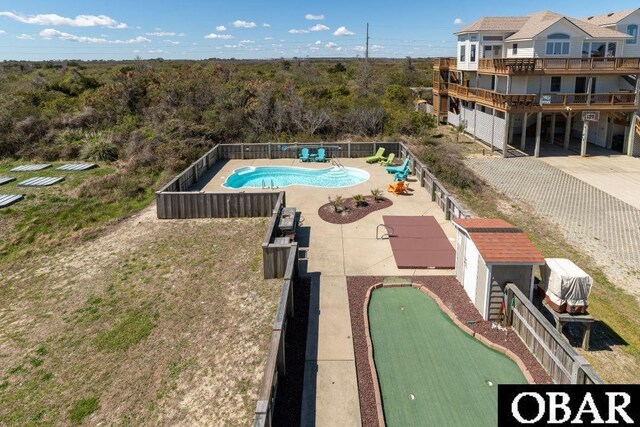 view of swimming pool with a fenced backyard, an outbuilding, a fenced in pool, and a patio