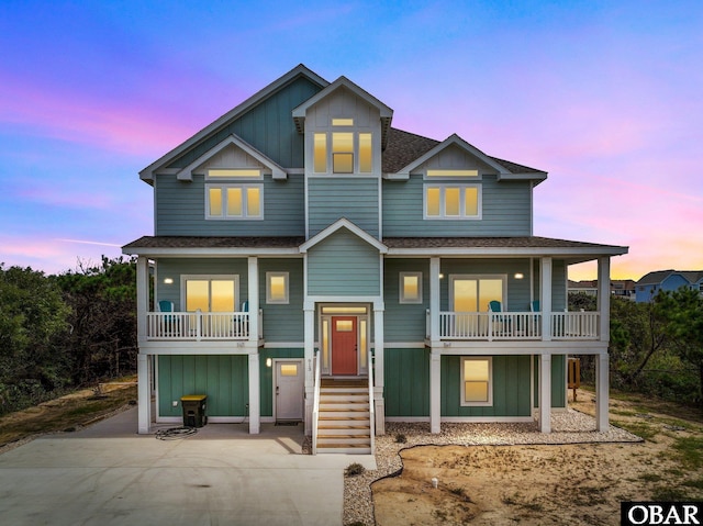 coastal home featuring a shingled roof, board and batten siding, and a balcony