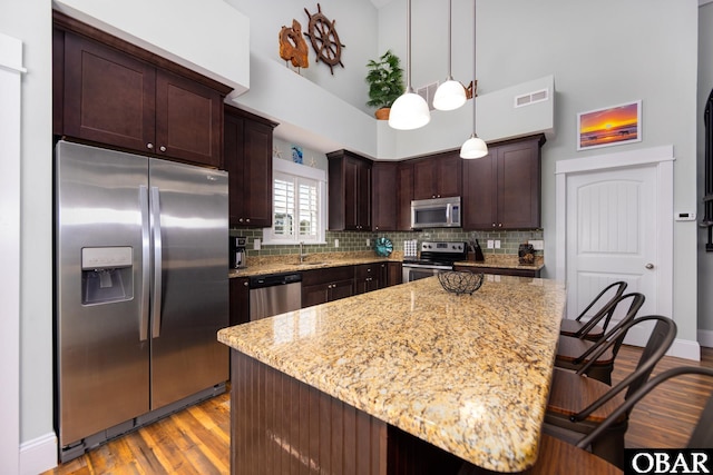 kitchen featuring dark brown cabinetry, tasteful backsplash, visible vents, light wood-style flooring, and stainless steel appliances