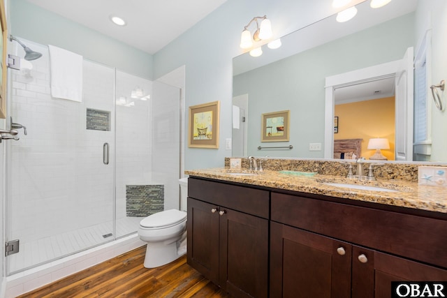 bathroom with double vanity, a stall shower, a sink, and wood finished floors